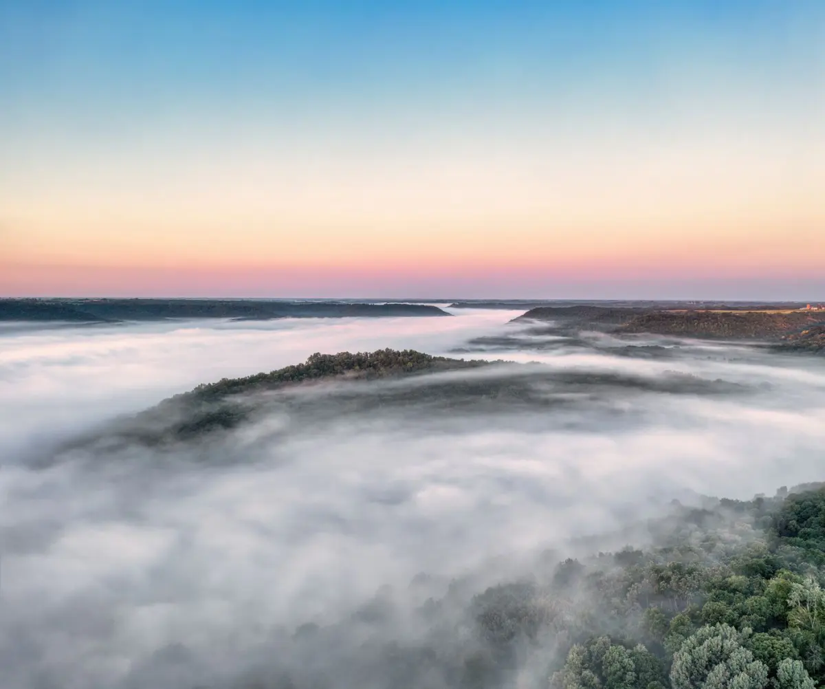 Morning fog filling a wooded river valley at dawn near Weaver, Minnesota