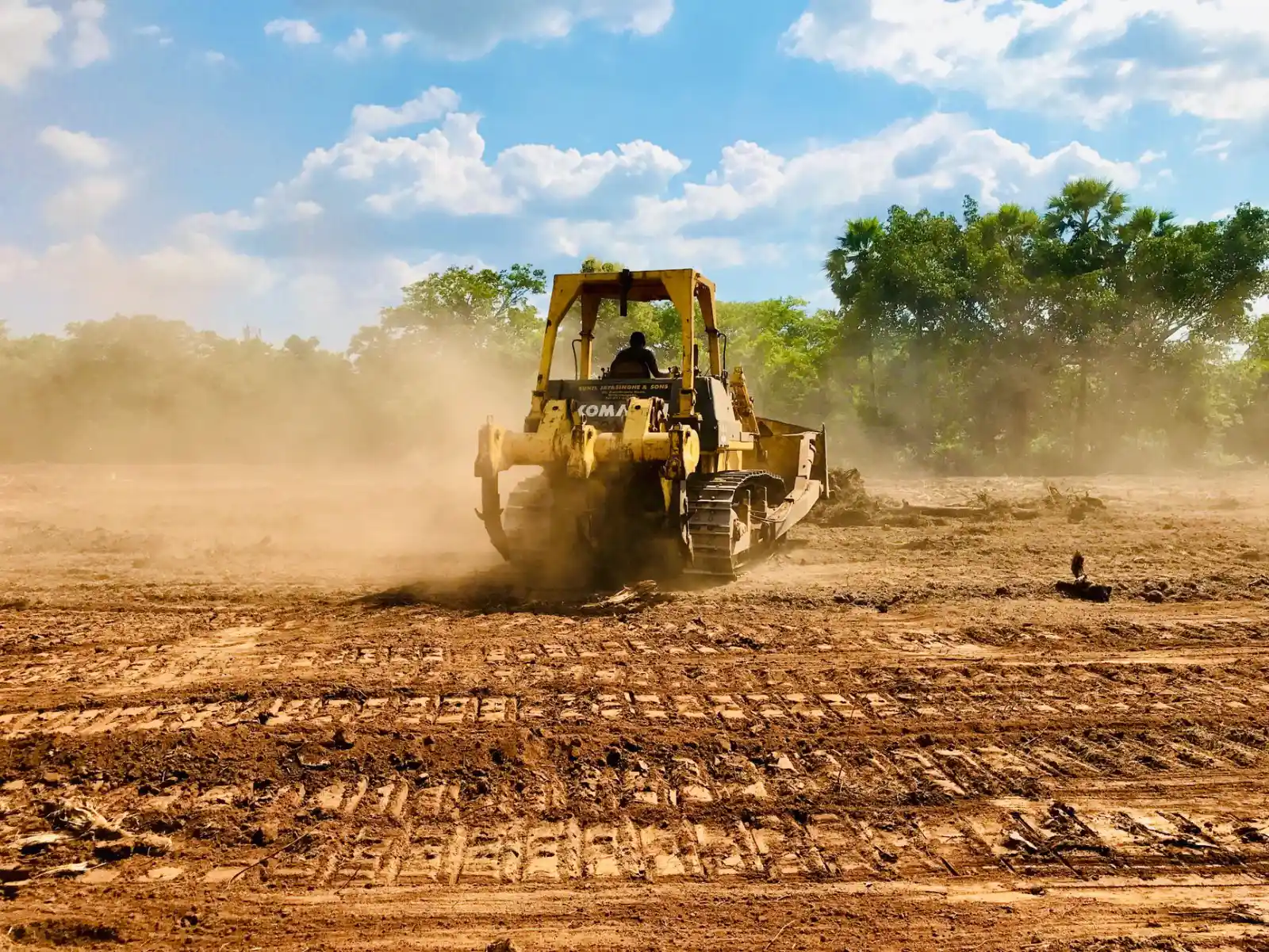 Bulldozer working across a dusty construction site during commercial land clearing