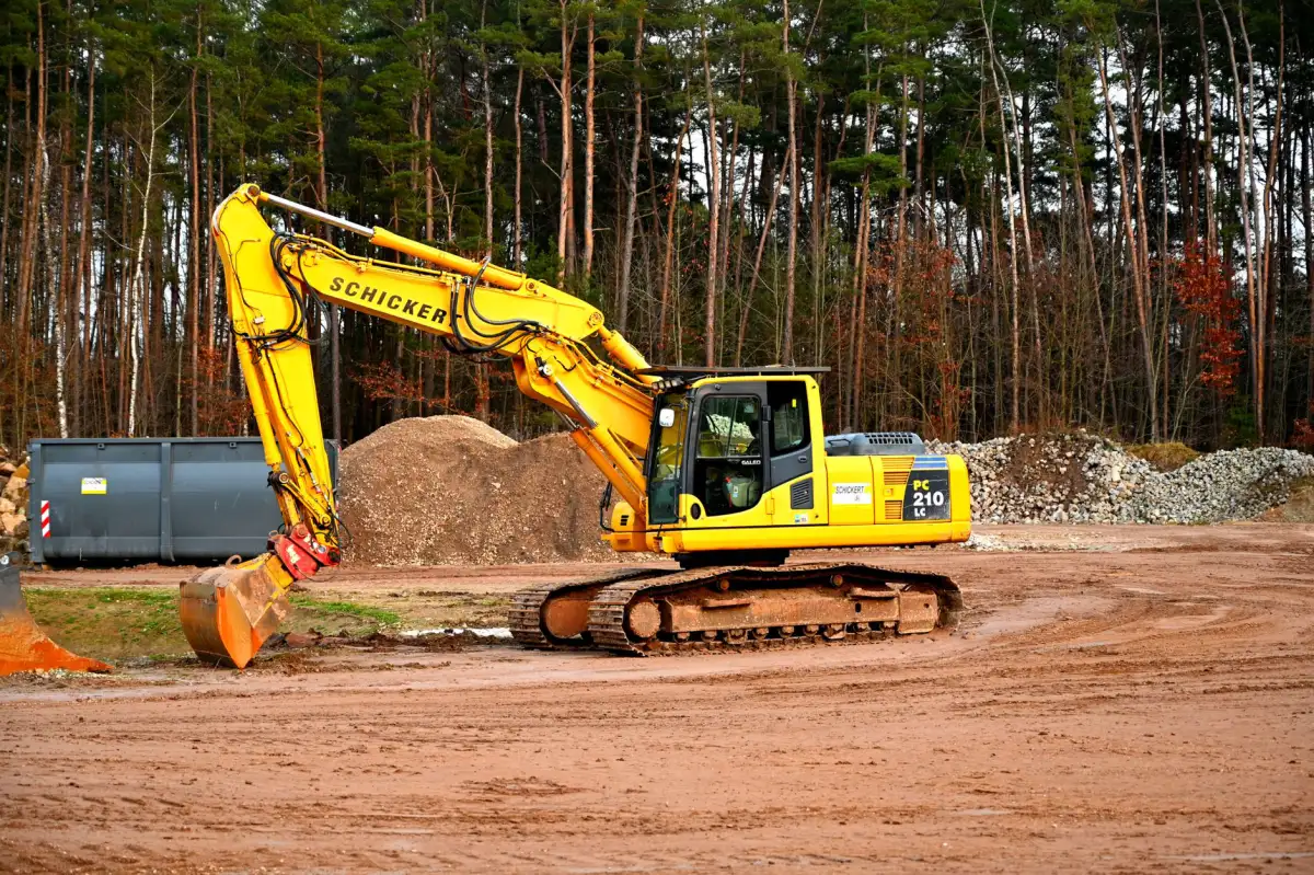 Excavator clearing trees and earth on a wooded construction site