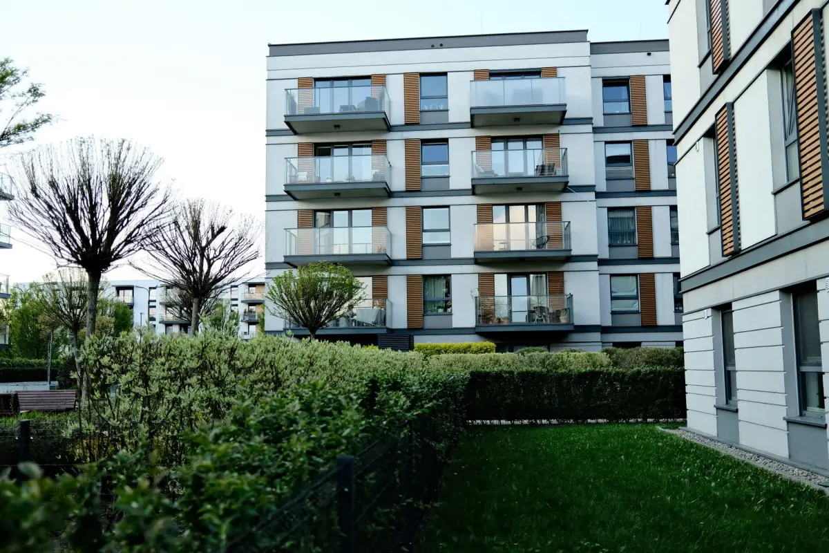 Multi-family apartment buildings with balconies and mature trees on the grounds